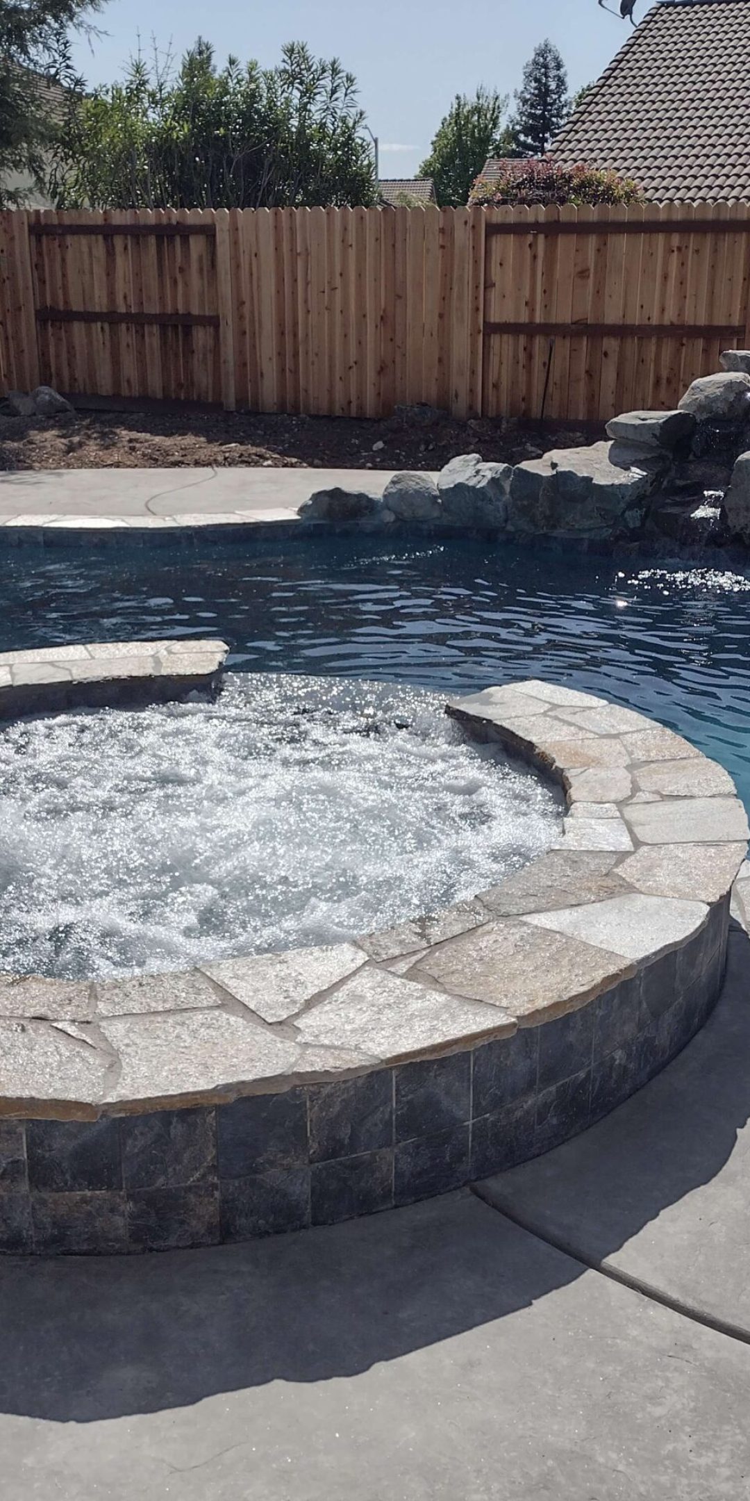 freeform pool with natural rock waterfall, bubbling spa,